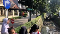 Anak-anak melihat alat berat yang mengeruk lumpur di anak sungai yang melintas di RW 09, Pondok Karya, Tangerang Selatan, Kamis (7/7/2022).