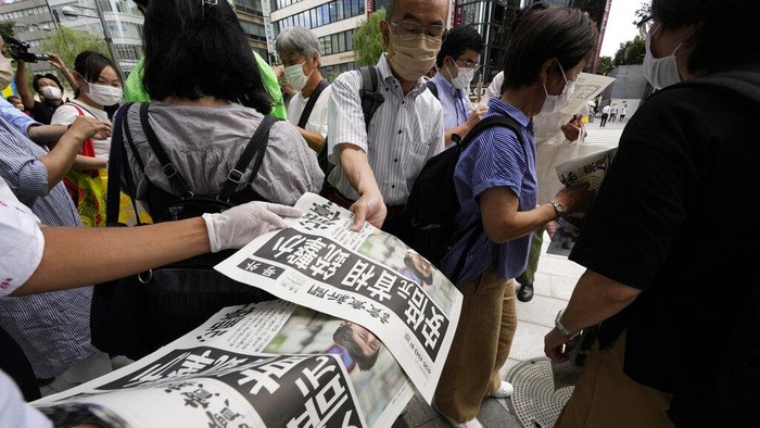 An employee distributes extra editions of the Yomiuri Shimbun newspaper reporting on Japan's former Prime Minister Shinzo Abe was shot, Friday, July 8, 2022, in Tokyo. Japan's former Prime Minister Shinzo Abe was shot during a campaign speech Friday in western Japan and was airlifted to a nearby hospital but he was not breathing and his heart had stopped, officials said. (AP Photo/Eugene Hoshiko)