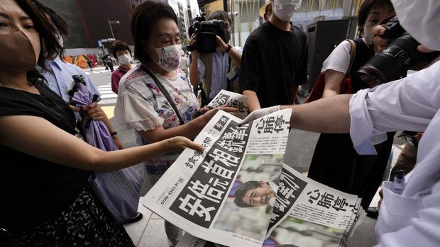 An employee distributes extra editions of the Yomiuri Shimbun newspaper reporting on Japan's former Prime Minister Shinzo Abe was shot, Friday, July 8, 2022, in Tokyo. Japan's former Prime Minister Shinzo Abe was shot during a campaign speech Friday in western Japan and was airlifted to a nearby hospital but he was not breathing and his heart had stopped, officials said. (AP Photo/Eugene Hoshiko)