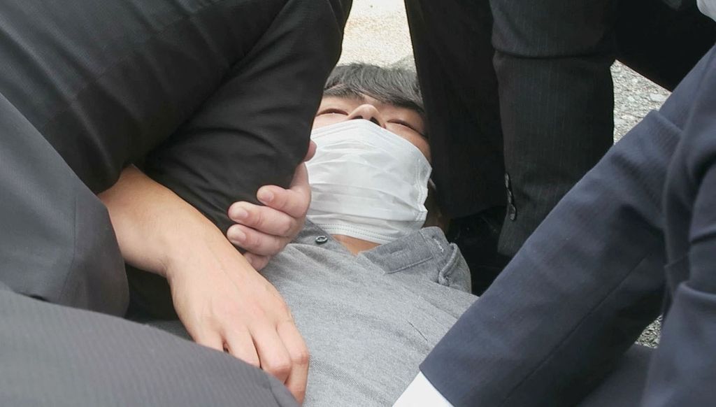 Tangkapan layar video menunjukkan seorang pria, yang diyakini telah menembak mantan Perdana Menteri Jepang Shinzo Abe, ditahan oleh petugas polisi di Nara, Jepang, Jumat (8/7/2022). (Kyodo/via REUTERS)
