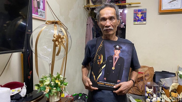 Udin, sopir angkot di Bandung saat memegang foto anaknya yang jadi polisi.