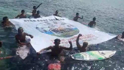 Komunitas peselancar membentangkan banner di tengah laut Sanur sebagai bentuk protes pembangunan terminal LNG di kawasan mangrove