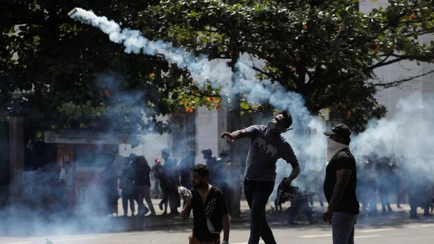 A demonstrator throws back a tear gas grenade towards police members as police use tear gas and water cannons to disperse demonstrators during a protest demanding the resignation of President Gotabaya Rajapaksa, amid the country's economic crisis, near the president's residence in Colombo, Sri Lanka, July 9, 2022. REUTERS/Dinuka Liyanawatte