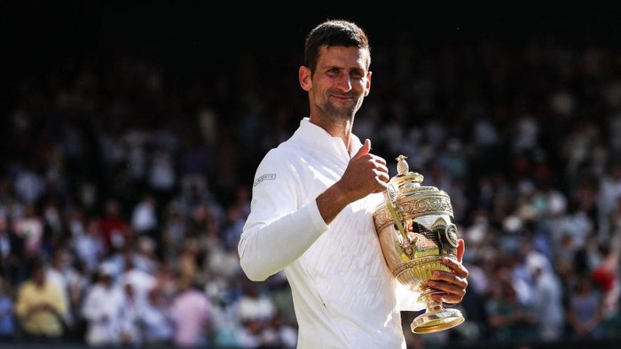 Serbias Novak Djokovic smiles as he holds his trophy after defeating Australias Nick Kyrgios during the mens singles final tennis match on the fourteenth day of the 2022 Wimbledon Championships at The All England Tennis Club in Wimbledon, southwest London, on July 10, 2022. - RESTRICTED TO EDITORIAL USE (Photo by Adrian DENNIS / AFP) / RESTRICTED TO EDITORIAL USE (Photo by ADRIAN DENNIS/AFP via Getty Images)