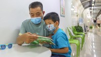 Seorang pria membacakan buku cerita kepada anak kecil di bunker yang kini dimanfaatkan untuk mendinginkan diri saat cuaca panas. (Yang Bo/China News Service via Getty Images).