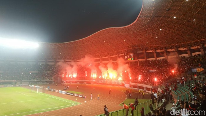 Suporter Timnas U-19 menyalakan flare di Stadion Patriot Candrabhaga, Minggu (10/7/2022).