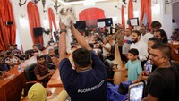 Demonstran mengangkat seekor anjing yang ditunjuk sebagai Menteri Satwa Liar yang baru di ruang rapat kabinet Presiden Gotabaya Rajapaksa yang berada di kediaman Presiden Sri Lanka, Kolombo, Minggu (10/7/2022). (REUTERS/Dinuka Liyanawatte).
