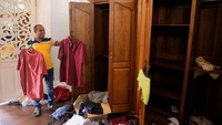 Seorang pria memegang baju milik Presiden Gotabaya Rajapaksa di dalam kediaman resmi presiden yang ramai diserbu oleh para pengunjuk rasa di Kolombo, Sri Lanka, Minggu (10/7/2022).