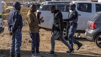 Petugas mengarahkan seorang warga untuk menjauh dari lokasi penembakan saat proses evakuasi dan penyelidikan tengah berlangsung di sebuah bar yang berada di kawasan Soweto, Afrika Selatan.