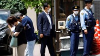 Dua orang warga berdoa di dekat kediaman Shinzo Abe di mana sejumlah petugas kepolisian tampak berjaga di sana. (REUTERS/ Kim Kyung-Hoon).