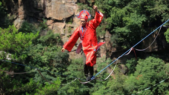 ZHANGJIAJIE, CHINA - JULY 10: Slackline walkers in traditional Chinese costumes compete during a high-altitude slackline competition at Zhangjiajie National Forest Park on July 10, 2022 in Zhangjiajie, Hunan Province of China. (Photo by VCG/VCG via Getty Images)