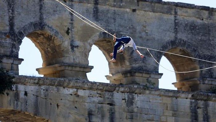 Aksi Nekat Pria Prancis Meniti Seutas Tali di Situs UNESCO VERS-PONT-DU-GARD, FRANCE - JULY 09: French tightrope walker Nathan Paulin walks on a slackline at the Pont du Gard, a Roman aqueduct bridge part of the UNESCO's list of World Heritage Site, in Vers-Pont-du-Gard southern France, during the Crater Surfaces festival,on July 9, 2022 in Vers-Pont-du-Gard, France. (Photo by Patrick Aventurier/Getty Images)