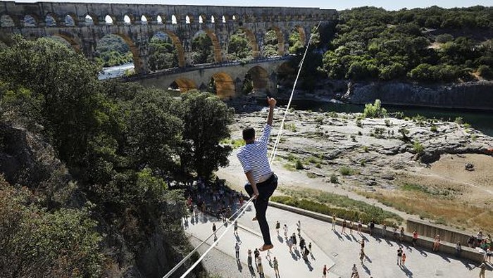 Aksi Nekat Pria Prancis Meniti Seutas Tali di Situs UNESCO VERS-PONT-DU-GARD, FRANCE - JULY 09: French tightrope walker Nathan Paulin walks on a slackline at the Pont du Gard, a Roman aqueduct bridge part of the UNESCO's list of World Heritage Site, in Vers-Pont-du-Gard southern France, during the Crater Surfaces festival,on July 9, 2022 in Vers-Pont-du-Gard, France. (Photo by Patrick Aventurier/Getty Images)