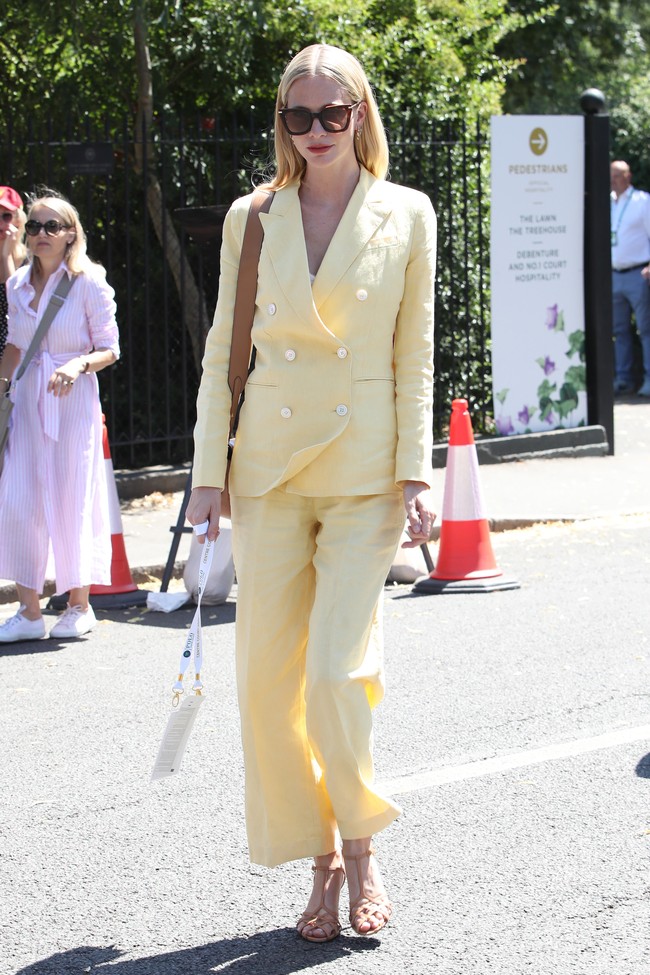 Sosialita Poppy Delevingne pun tak melewatkan final Wimbledon 2022. Ia menebar pesonanya dengan setelan kuning yang cerah, berikut sandal heels kulit dan tas senada. (Foto: GC Images/Neil Mockford)