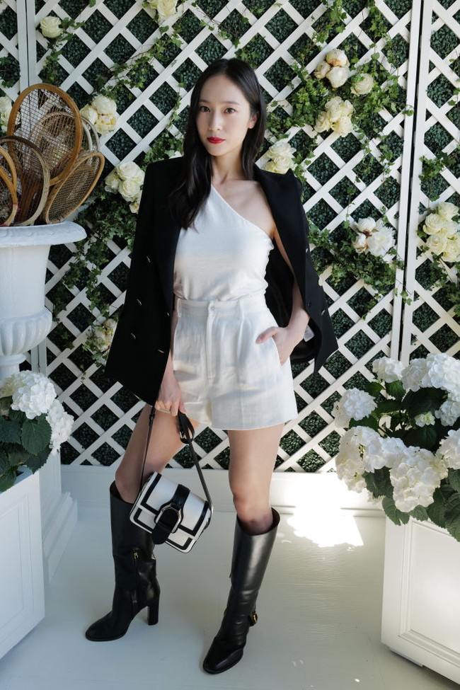 Penyanyi Amerika Serikat berdarah Korea Krystal Jung juga hadir di Wimbledon 2022. Ia tampil stylish dalam balutan atasan berbahu asimetris dan celana penk putih yang dipadu jas dan boots hitam, sertas tas beraksen belt bucket. Semuanya koleksi Ralph Lauren. (Foto: WireImage for Ralph Lauren/Darren Gerrish)