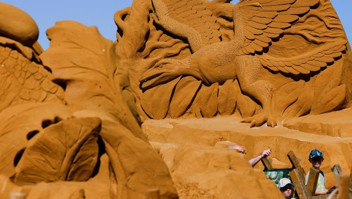Mengunjungi Festival Patung Pasir Dinosaurus di Belgia A visitor walks between sculptures during the Sand Sculpture Festival