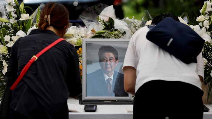 A portrait photo of late former Japanese Prime Minister Shinzo Abe, who was shot while campaigning for a parliamentary election, is placed on an altar as a mourner bows, at the Liberal Democratic Party (LDP) headquarters, in Tokyo, Japan July 11, 2022. REUTERS/Issei Kato