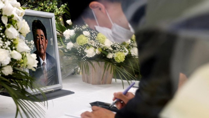 A portrait photo of late former Japanese Prime Minister Shinzo Abe, who was shot while campaigning for a parliamentary election, is placed on an altar as a mourner bows, at the Liberal Democratic Party (LDP) headquarters, in Tokyo, Japan July 11, 2022. REUTERS/Issei Kato