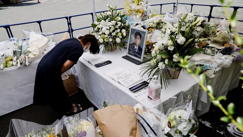 A portrait photo of late former Japanese Prime Minister Shinzo Abe, who was shot while campaigning for a parliamentary election, is placed on an altar as a mourner bows, at the Liberal Democratic Party (LDP) headquarters, in Tokyo, Japan July 11, 2022. REUTERS/Issei Kato