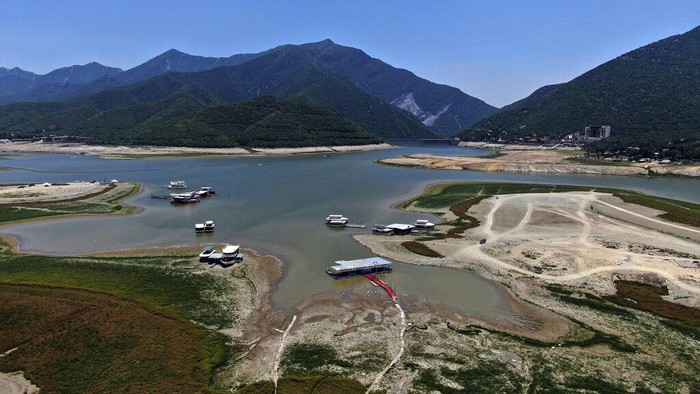 Potret Meksiko Dilanda Kekeringan Hebat Dry, cracked land and boats is visible in The Boca reservoir that supplies water to the northern city of Monterrey is almost dry as the northern part of Mexico is affected by an intense drought, in Santiago, Mexico, Saturday, July 9, 2022. Local authorities began restricting water supplies in March, as a combination of an intense drought, poor planning and high use has left the three dams that help supply the city dried up, with thousands of homes not receiving any water for weeks. (AP Photo/Fernando Llano)