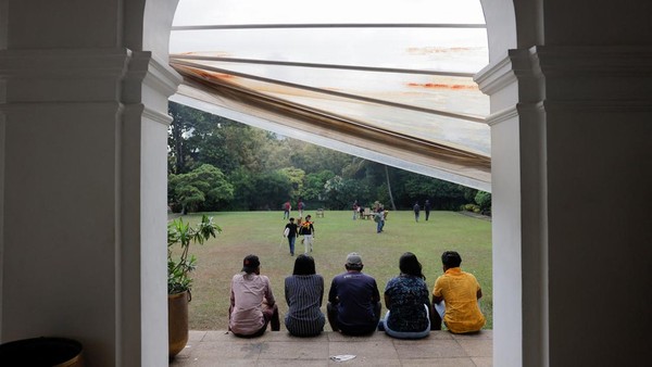 Warga yang merangsek masuk, asyik duduk santai di teras taman rumah PM Sri Lanka. Aksi protes ini dimanfaatkan warga dengan menikmati sejumlah fasilitas yang ada di rumah Presiden Gotabaya Rajapaksa dan PM Sri Lanka.