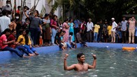 Seorang pria berpose di dalam kolam renang di rumah presiden Sri Lanka. Sejumlah orang lainnya asyik bermain dan berfoto di pinggir kolam renang.