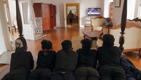 Sejumlah orang terlihat tiduran di atas tempat tidur sambil menonton televisi.