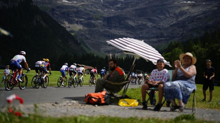 Sederet Lansekap Indah yang Dilintasi Pebalap TDF 2022 Spectators watch the breakaway group pass during the ninth stage of the Tour de France cycling race over 193 kilometers (119.9 miles) with start in Aigle, Switzerland and finish in Chatel les Portes du Soleil, France, Sunday, July 10, 2022. (AP Photo/Thibault Camus)