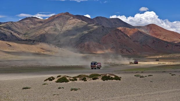 Plateau Mora, Jammu and Kashmir, India - July 23rd, 2011: Red trucks with fuel driving on tableland Mora(4800m), Leh-Manali road, Indian Himalaya.