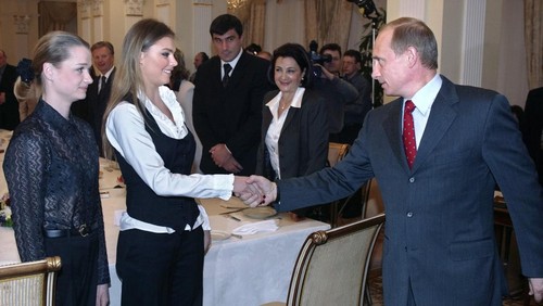Russian President Vladimir Putin (R) shakes hands with famous Russian gymnasts Alina Kabayeva (C) and Svetlana Khorkina (L) during the meeting with sportsmen, candidates to Russian Olympic team for Olympics 2004, in the presidential residence in Novo-Ogaryovo outside Moscow, 10 March 2004. Vladimir Putin said Russian business is ready to support Russian sportsmen. AFP PHOTO / POOL        (Photo credit should read SERGEI CHIRIKOV/AFP via Getty Images)