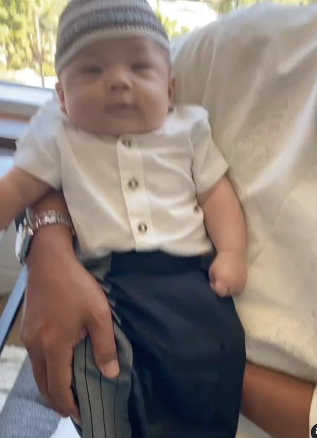 Nikita tampak mendandani sang anak dengan kemeja berwarna putih dan sarung berwarna biru navy dengan aksen garis-garis pada bagian sampingnya. Tak lupa baby Izz juga dipakaikan sebuah peci berwarna senada di kepalanya. Foto: Instagram/@yorafebrina
