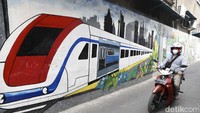 Pengenadara sepeda motor melintasi sisi tembok dengan gambar MRT.