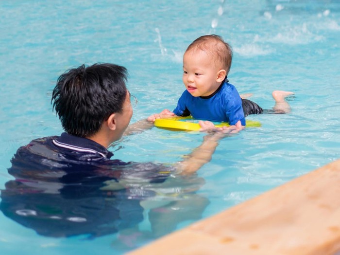 Asian Father take Cute little Asian 18 months / 1 year old toddler baby boy child to swimming class in Thailand, Happy infant enjoying his first swim in pool with his dad, Selective focus