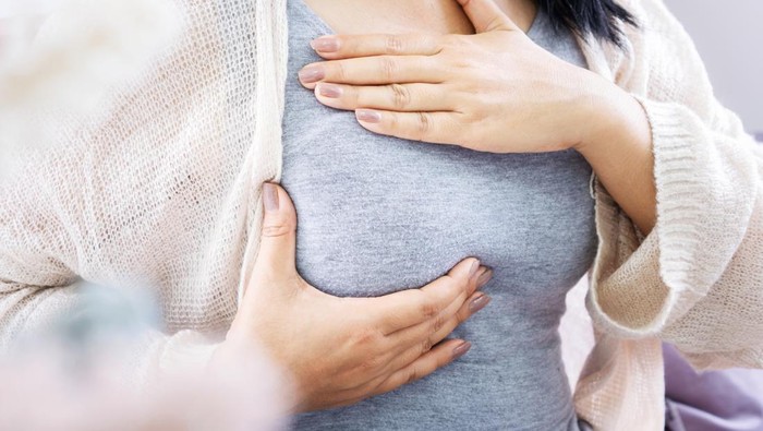 ilustrasi payudara closeup woman hands self breast examination hand checking her breast cancer sign
