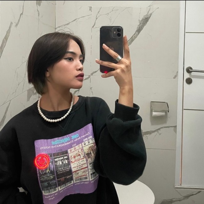 Agar lebih mempesona, Jeje menambahkan penampilannya dengan beberapa aksesori tambahan. Seoerti dalam foto, Jeje yang tengah mengenakan sweater hitam tampak memadukannya dengan kalung mutiara berwarna putih dan cincin berwarna perak. Foto: Instagram/@911jelicascalling