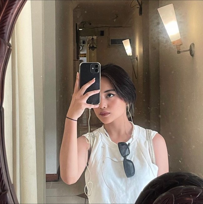 Mengenakan sleeveless top berwarna putih dengan dipadukan kalung mutiara, penampilan Jeje terlihat edgy. Untuk membuat gayanya lebih stylish, Jeje tampak mengenakan kaca mata hitam yang digantungkan di leher bajunya. Foto: Instagram/@911jelicascalling