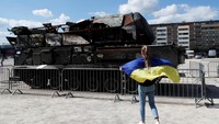 Seorang wanita memegang bendera Ukraina melihat peralatan militer Rusia yang dihancurkan oleh Angkatan Bersenjata Ukraina yang dipamerkan di Ceko.