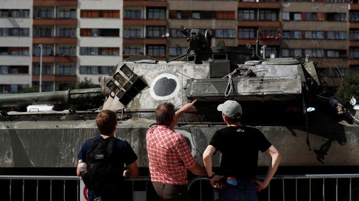 Kendaraan Tempur Rusia yang Dihancurkan Ukraina Jadi Tontonan A woman holding a Ukrainian flag looks at Russian military equipment destroyed by the Armed Forces of Ukraine displayed, as Russia's attack on Ukraine continues, in Prague, Czech Republic, July 11, 2022. REUTERS/David W Cerny