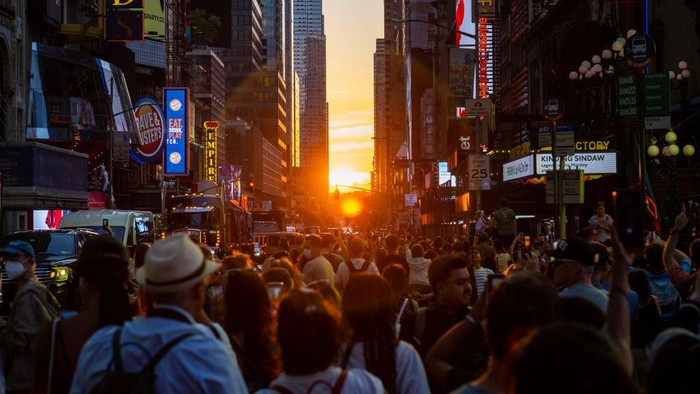 NEW YORK, NEW YORK - JULY 11: Hundreds of people gather around to watch the sun set during Manhattanhenge in Times Square on July 11, 2022 in New York City. Manhattanhenge, which happened in May and now again in July, is the phenomenon when the sunset lines up between certain blocks in New York City. (Photo by Alexi Rosenfeld/Getty Images)