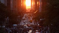 Matahari terbenam di atas Manhattan di 42nd street selama Manhattanhenge di New York, Senin, (11/7/2022). Cahaya emas senjakala terlihat apik di sini, tepat di antara gedung pencakar langit Kota New York. (Yuki Iwamura/AFP/Getty Images)