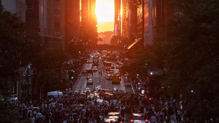 Menikmati Indahnya Manhattanghenge di Langit New York People take picture as the sun sets over Manhattan on 42nd street during the
