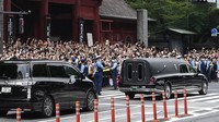 Mobil jenazah akan membawa jasad PM Jepang dengan masa jabatan terpanjang itu dari rumah duka di Kuil Zojoji, Tokyo, ke Aula Pemakaman Kirigaya untuk dikremasi. Di luar kuil, ribuan orang berkumpul memberikan penghormatan terakhir untuk Abe. Warga melambaikan tangan, mengabadikan momen dengan kamera ponsel. (AP/Hiro Komae)