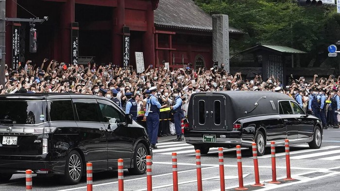 The vehicle, right, carrying the body of former Japanese Prime Minister Shinzo Abe leaves Zojoji temple after his funeral in Tokyo on Tuesday, July 12, 2022. Abe was assassinated Friday while campaigning in Nara, western Japan. (AP Photo/Hiro Komae)