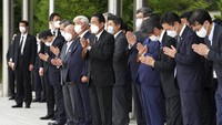 Perdana Menteri Jepang Fumio Kishida (tengah) dengan pejabat dan karyawan berdoa di depan mobil jenazah yang membawa jenazah mantan PM Shinzo Abe, saat kendaraan tersebut melakukan kunjungan singkat ke Kantor Perdana Menteri. (AP/Eugene Hoshiko)