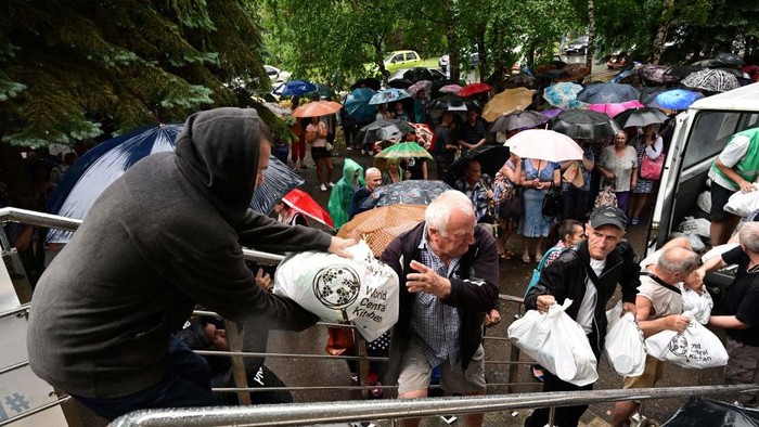 Warga Ukraina Hujan-hujanan Demi Bantuan Makanan Volunteers help to bring food rations to a food aid distribution center, managed by different NGOs and called