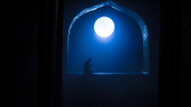 A realistic Arabian interior miniature with window and columns. Silhouette of muslim praying on carpet near window. Festive greeting card, invitation for Muslim holy month Ramadan Kareem. Selective focus