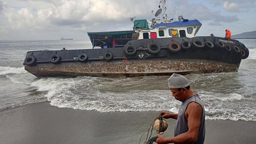 Kapal tongkang dan tugboat-nya masih berada di pesisir Pantai Tanah Ampo, Rabu (13/7/2022). Kapal tongkang tersebut terdampar pada Senin (11/7/2022) malam dan hingga kini proses evakuasi masih diupayakan.
