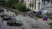 Tampak sejumlah warga berkumpul untuk mendapatkan bantuan kemanusiaan di dekat pameran tank dan senjata yang diamankan dari pasukan Ukraina di Lisichansk.