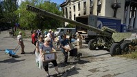 Warga ramai-ramai mengangkut bantuan kemanusiaan di dekat pameran tank dan senjata pasukan Ukraina di kawasan Lisichansk yang berada di bawah kendali Pemerintah Republik Rakyat Luhansk, Ukraina timur.