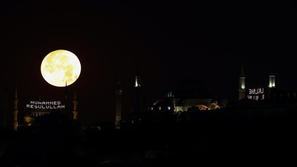 Pemandangan bulan purnama yang menghiasi dua bangunan ikonik tersebut memanjakan mata siapa saja yang melihatnya. (Ali Atmaca/Anadolu Agency/Getty Images).